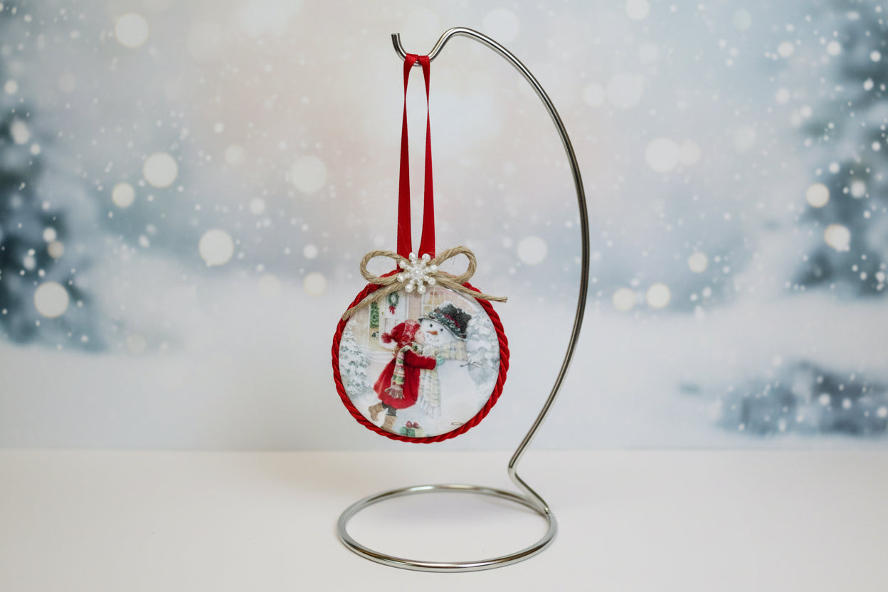 Decorative Christmas ornament with a girl kissing a snowman design on a white background