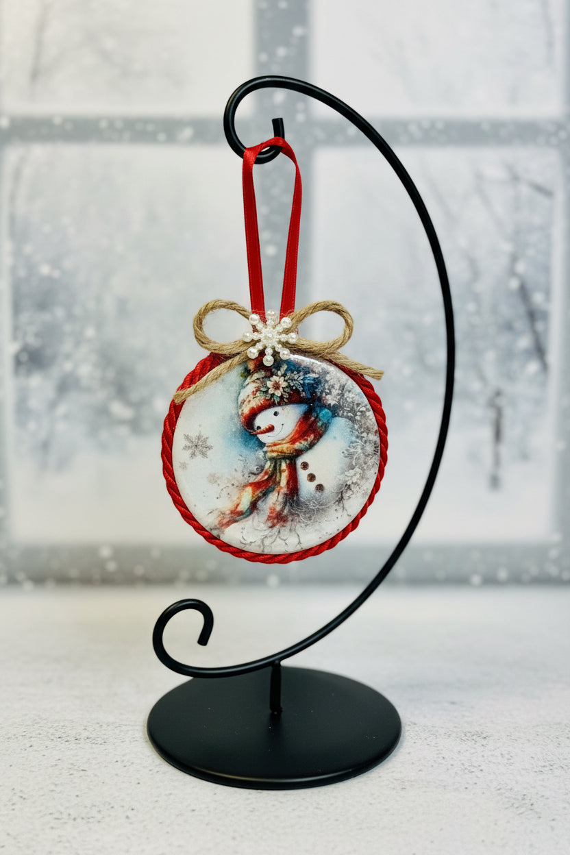 Decorative ornament with snowman design on a red string against a light background