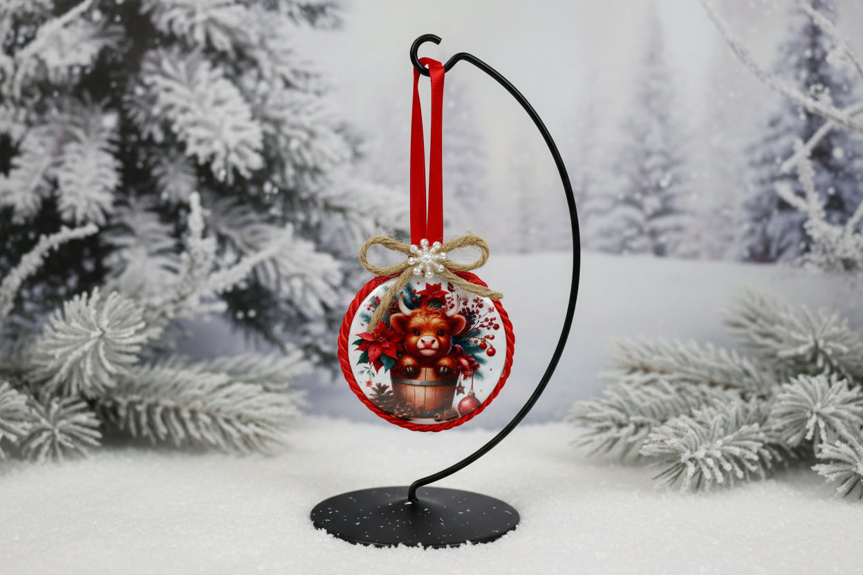 Decorative Christmas ornament with a holiday Highland cow design on a plain background